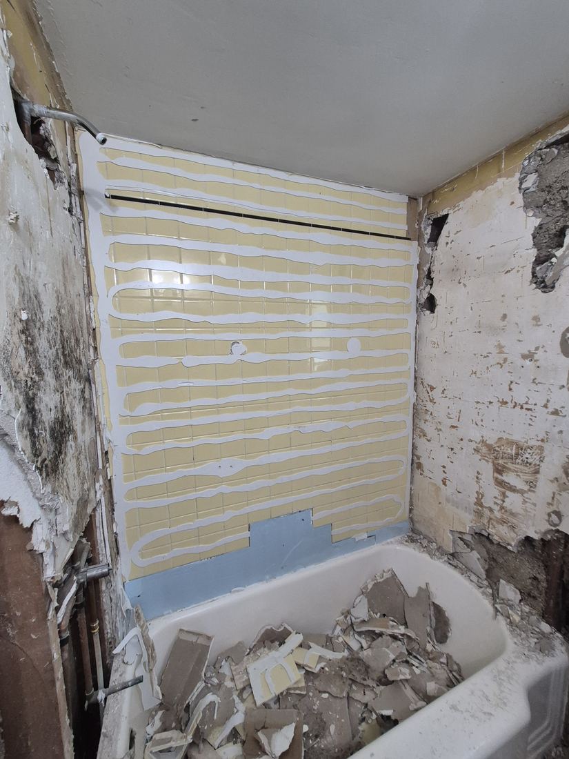 Bathroom in Beverly, MA before remodel, with the tub walls torn out and framing exposed