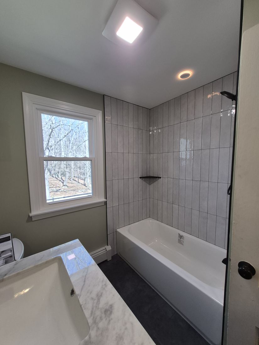 Bathroom in Boxford, MA after remodel with vertical tile tub surround, glass panel and dark floor