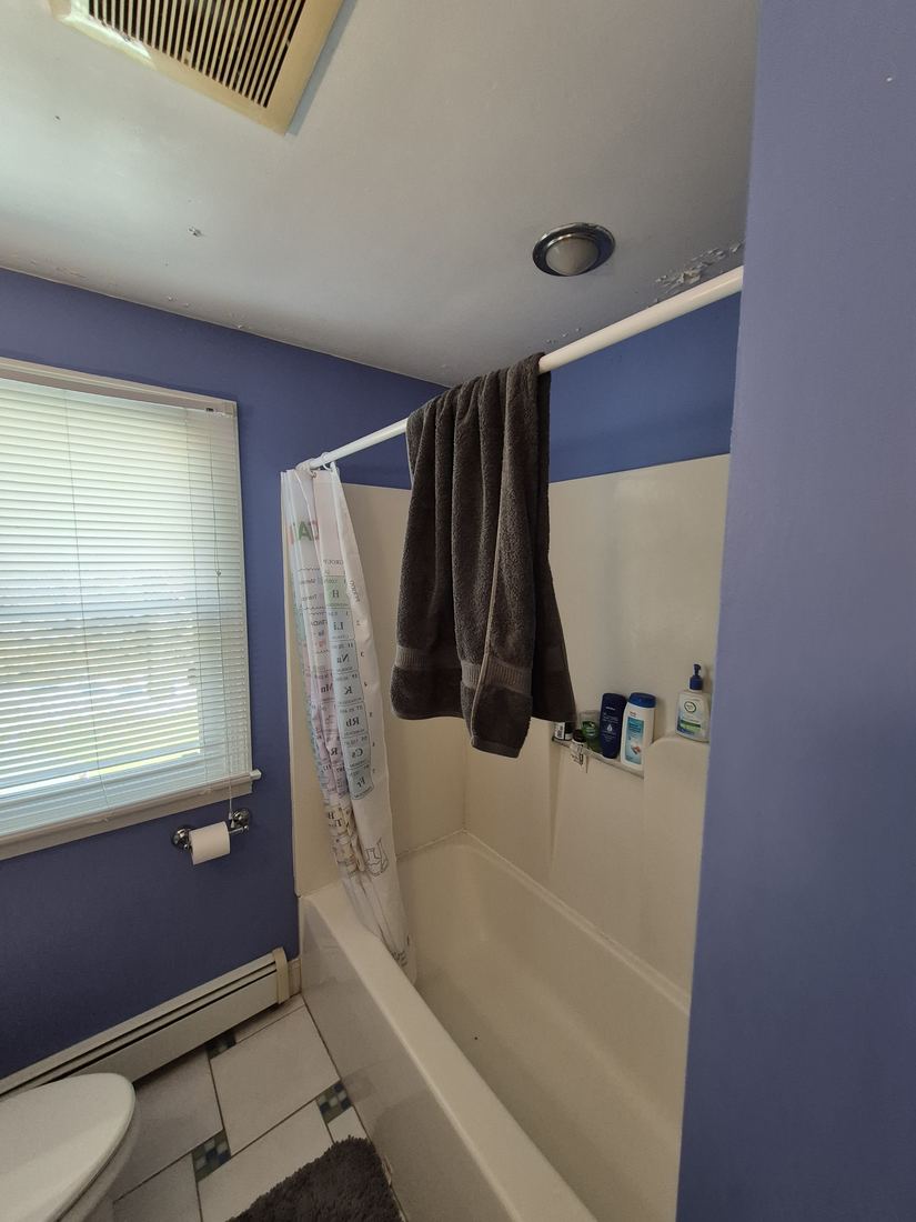 Bathroom in Boxford, MA before remodel with blue walls and a fiberglass tub surround