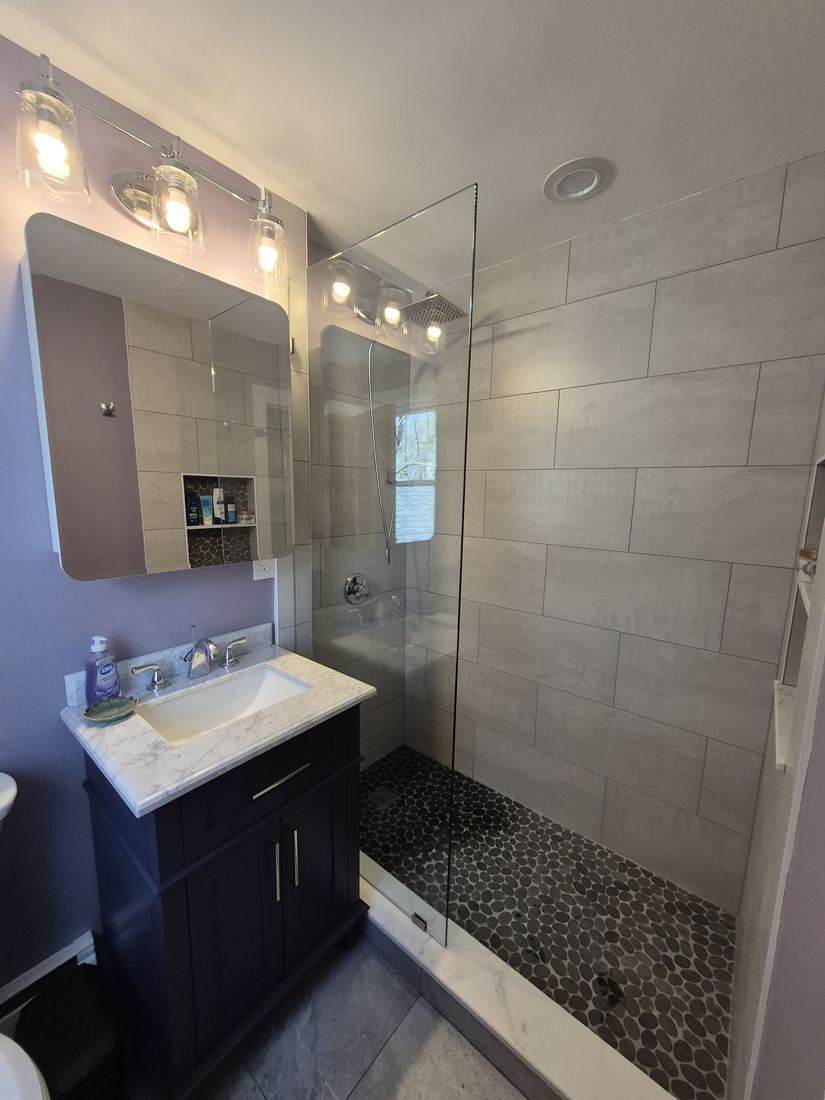 Bathroom in Boxford, MA after shower rebuild with glass walk-in shower, large-format tile and new vanity