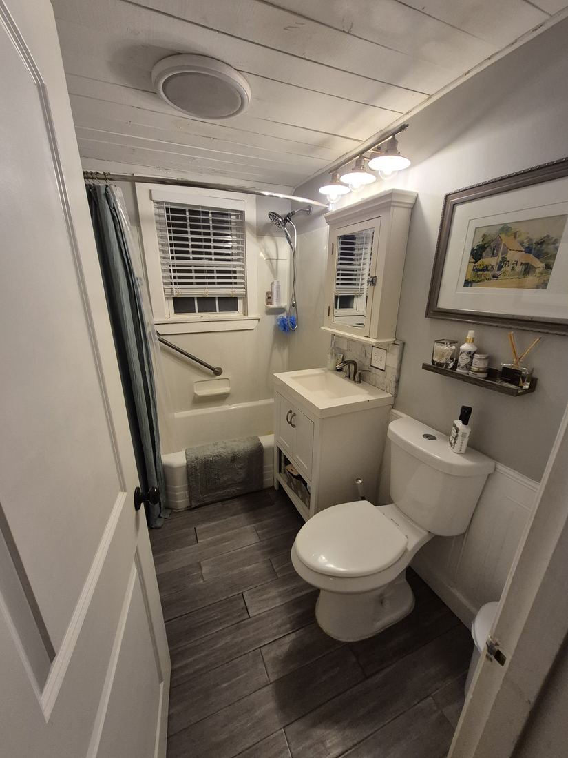 Bathroom in Danvers, MA before remodel with dark floor and wood-plank ceiling