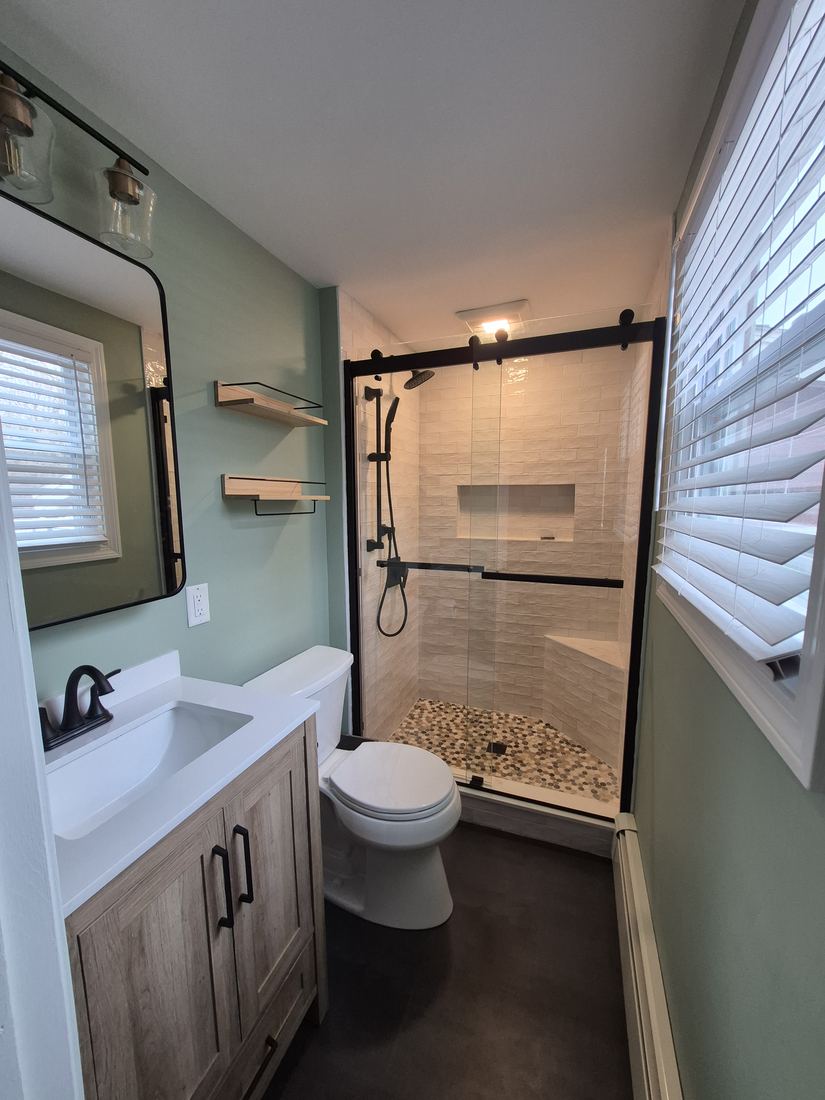 Bathroom in Danvers, MA after shower rebuild with sliding glass door, tiled shower and wood vanity
