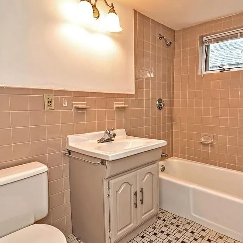 Bathroom before refresh in Lynn, MA with pink wall tile, old vanity and patterned floor