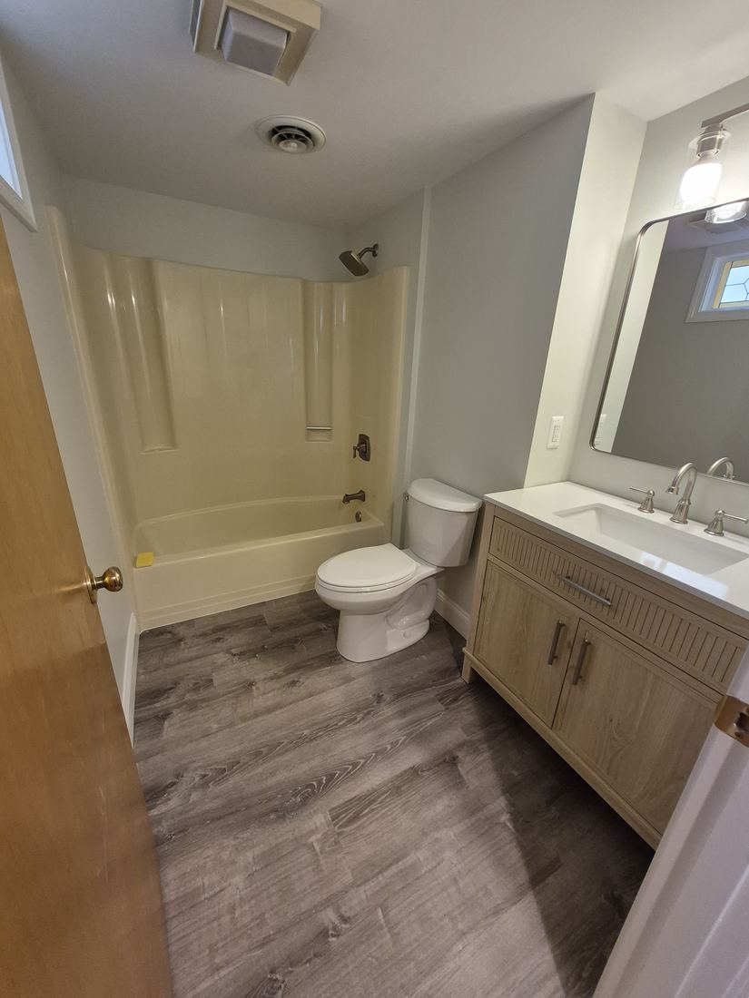 Bathroom in Salem, MA after refresh with new vanity, mirror and wood-look flooring