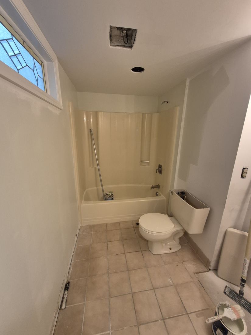 Bathroom in Salem, MA before refresh with beige tile floor and fiberglass tub