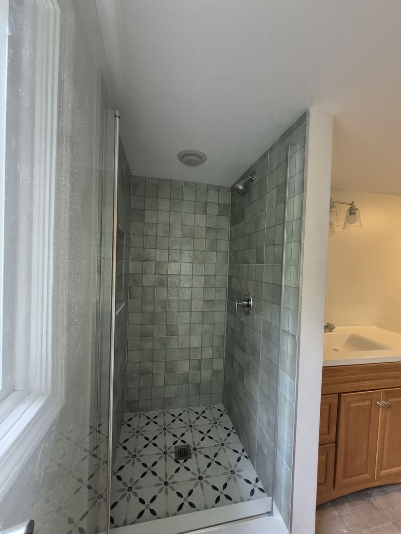Bathroom in Salem, MA after remodel with a tiled shower, glass door and patterned floor tile