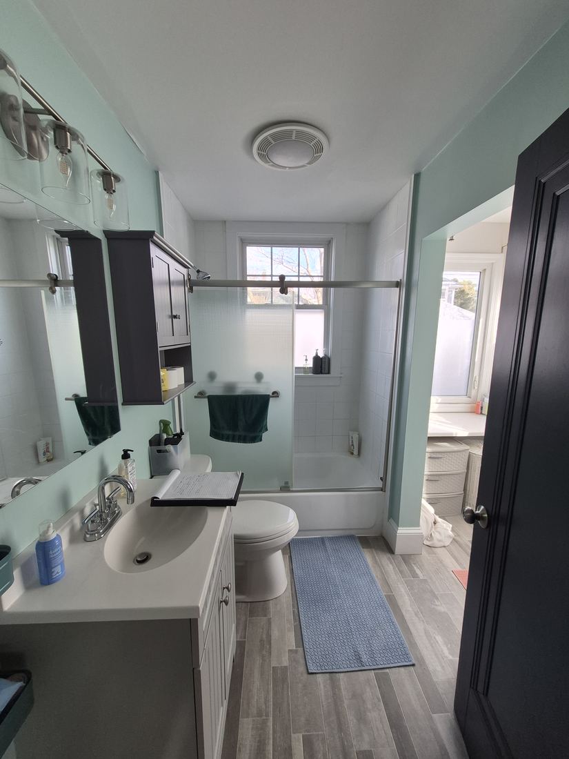 Bathroom in Salem, MA before tub-to-shower conversion with sliding tub doors and gray vanity